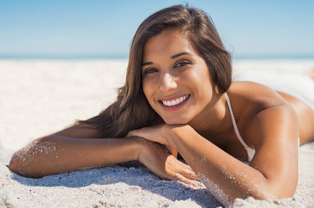 istock Smiling woman lying on sand 928866882