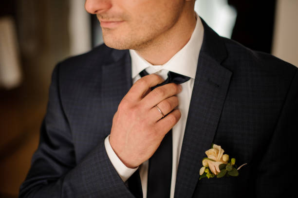 istock Handsome groom getting dressed in wedding suit with boutonniere 928867326