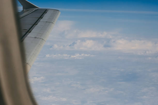 istock Looking thru airplane 's window seeing wing of airplane , white clouds and blue sky 928869684