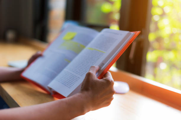 istock close-up for hand young students reading a book  in coffee cafe; work at home. 928878538