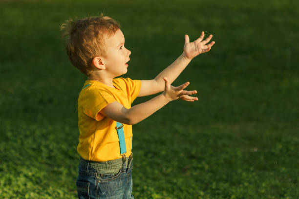 istock Cute red-haired boy reaches out to the sunset. 928880830