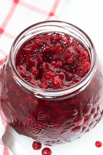 istock glass jar of cranberry jam on a white table, vertical 928882488