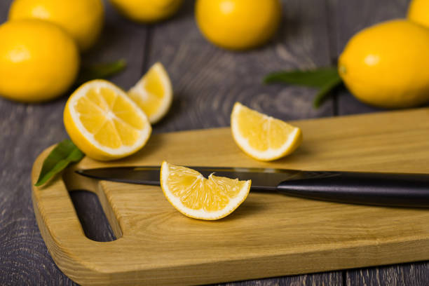 istock Whole citrus, sliced lemon slices and knife on cutting Board, on table 928891610