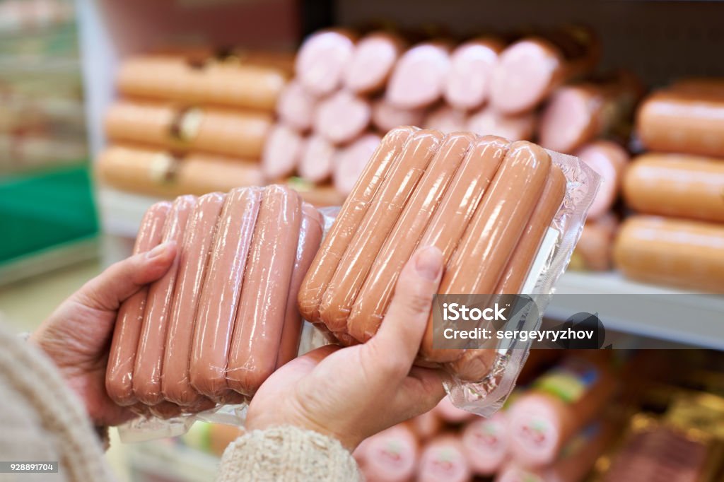 Woman chooses sausages in vacuum package at store Woman chooses sausages in a vacuum package at the grocery store Sausage Stock Photo