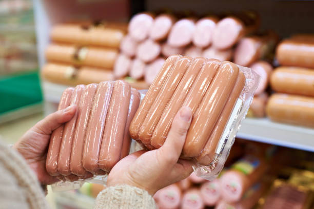 woman chooses sausages in vacuum package at store - airtight packing meat food imagens e fotografias de stock
