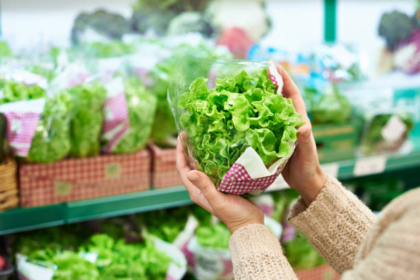 Woman chooses green leaf salad in grocery store