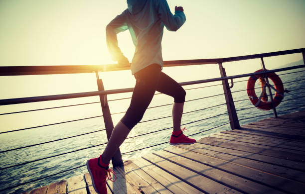 istock sporty female runner running on seaside boardwalk during sunrise 928894550