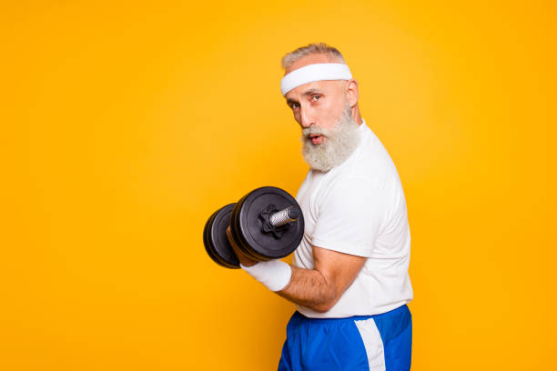 cool playful flirty naughty strong grandpa with confident grimace exercising holding equipment up, lifts it with strength and power. body care, fitness, body building, hobby, weight loss lifestyle - beautiful one person strength sensuality imagens e fotografias de stock