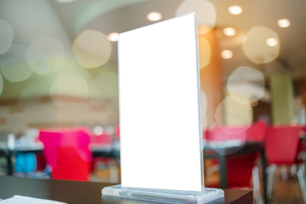 istock Mock up white Label for blank menu frame in Bar restaurant cafe., Stand for booklets with  sheets paper tent card on table cafeteria, blurred background insert for text of customer. Space for texting. 928902278