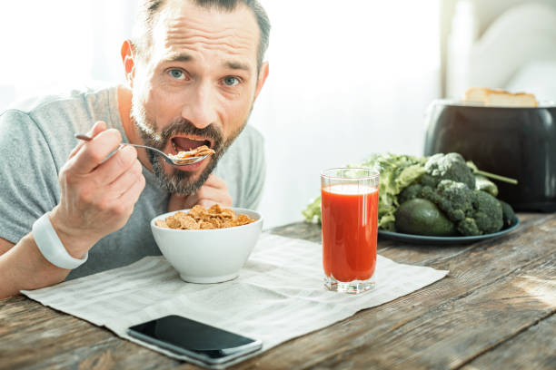 istock Handsome pleasant man holding a spoon and eating flakes 928902980