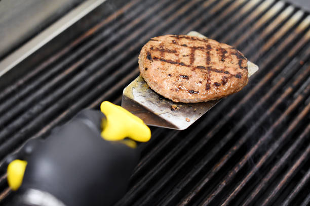 istock Chef cooking a hamburger patty on a grill 928905756