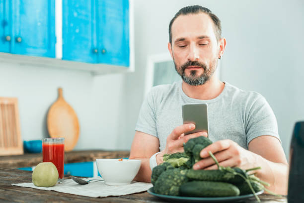 istock Calm pleasant man using his cellphone touching a broccoli 928909316