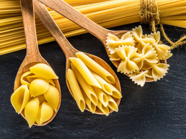 istock Different pasta types in wooden spoons. 928916896