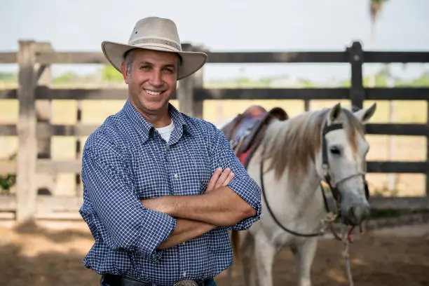 Photo of Portrait of a happy cowboy at a ranch with a horse