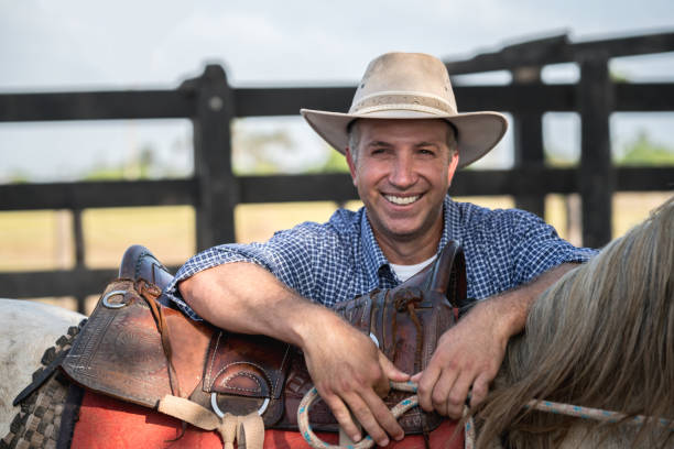 istock Happy cowboy working at a ranch with horses 928917554