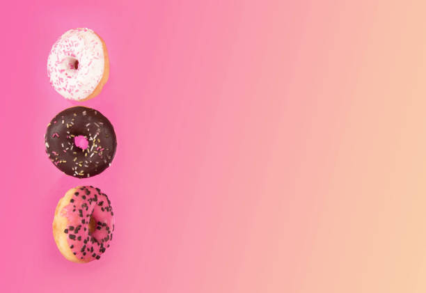 istock Colorful glazed donuts in motion on pink background 928918276