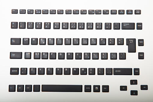Loose alphanumeric covers for the keys on a computer keyboard on a white or light silver background viewed from overhead centered in the screen with surrounding copy space