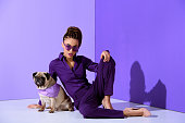 istock fashionable african american girl posing in purple suit with pug, ultra violet trend 928953942