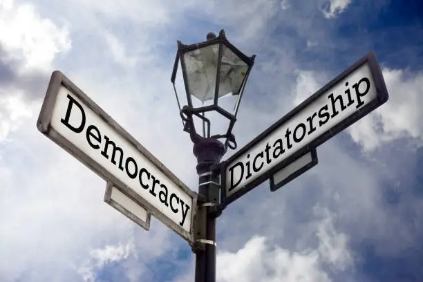 Street sign illustrating the concept of Democracy versus Dictatorship.