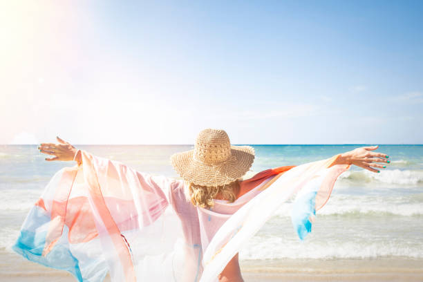 istock Woman With Textile Wearing Hat While Standing At Beach Against Clear Sky During Sunny Day 928964594
