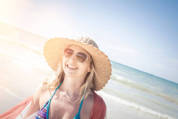 istock Smiling Woman Wearing Hat While Standing At Beach During Sunny Day 928965884