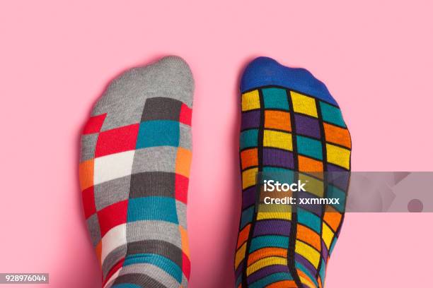 Photo libre de droit de Pied En Différentes Chaussettes Colorées Sur Fond Rose banque d'images et plus d'images libres de droit de Chaussette