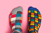 Foot in different colorful socks on pink background