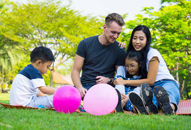 istock Happy Family Resting On Grassy Field At Park 928992042