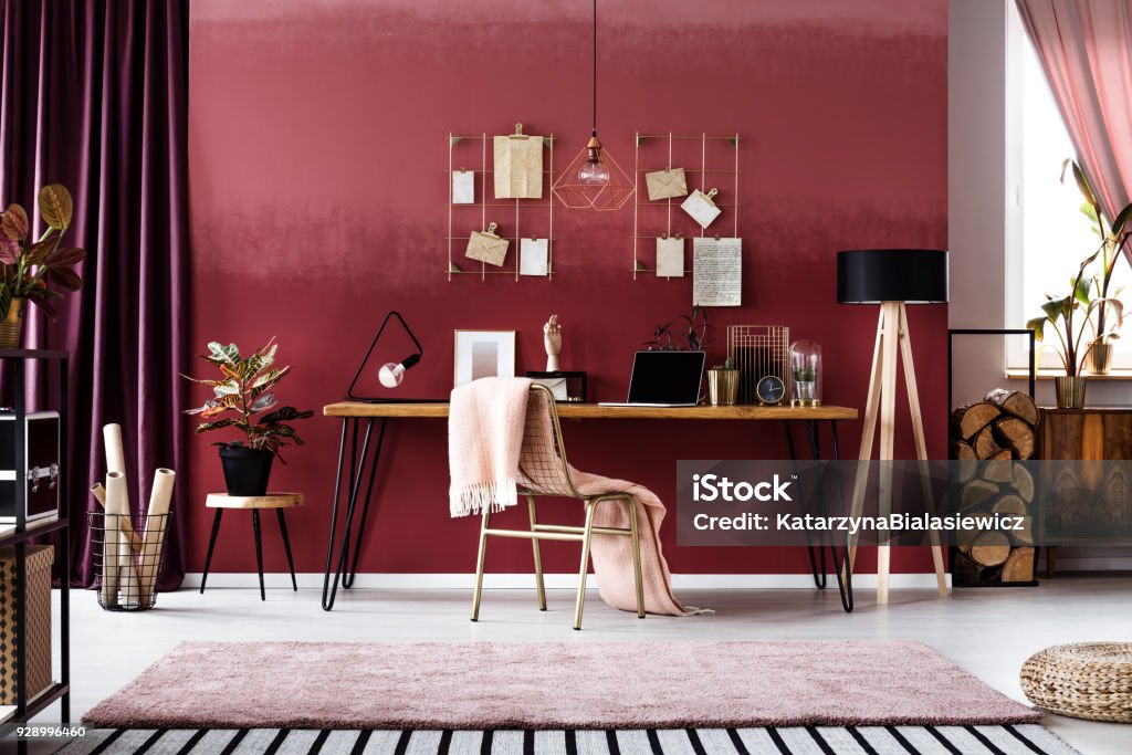 Cherry home office interior Pink blanket on metal chair next to wooden table in cherry home office interior with plant on stool Home Office Stock Photo