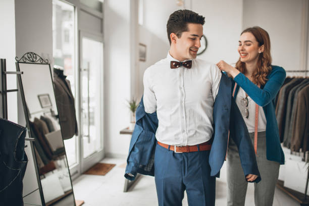 Let me assist you A fashion designer helpig her customer to choose and dress suit jacket woman tailor stock pictures, royalty-free photos & images