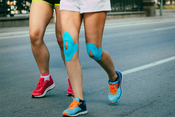 istock female runner blue kinesio tape on knees running on asphalt 929005652