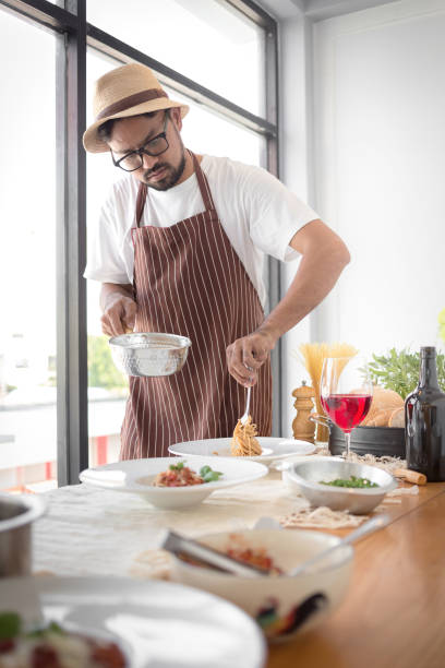 istock Handsome bearded cheef cook prepairing spaghetti on a kitchen, Chef cooks meal 929008558