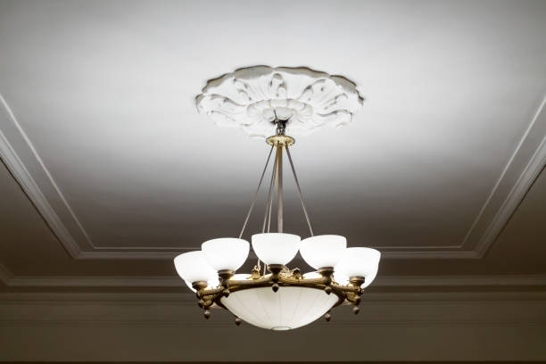 vintage chandelier hanging under white ceiling with stucco moldings