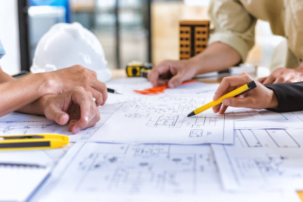 チーム エンジニアのイメージは、オフィスのデスクでエンジニア リング ツールと新しいプロジェクトの構築設計図をチェックします。 - architecture blueprint built structure construction ストックフォトと画像
