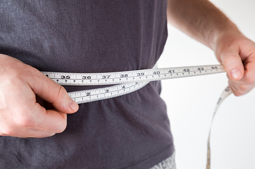 Hombre delgado midiendo su cintura. Estilo de vida saludable, cuerpo que adelgaza, concepto de pérdida de peso. Se preocupa por el cuerpo. photo