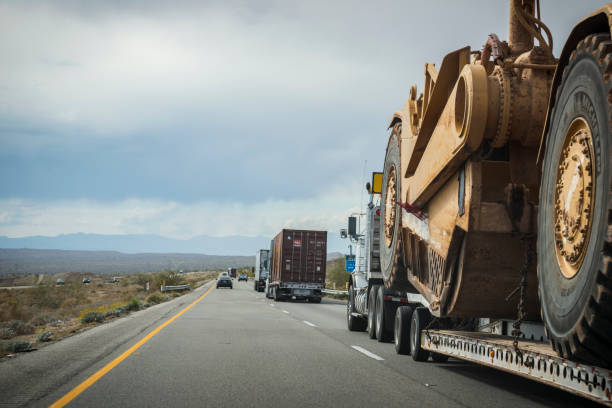 Transporting large Caterpillar wheel tractor-scraper on highway A truck transports a large Caterpillar wheel tractor-scraper on I-10 near Palm Springs, California. (March 18 2015) road scraper stock pictures, royalty-free photos & images