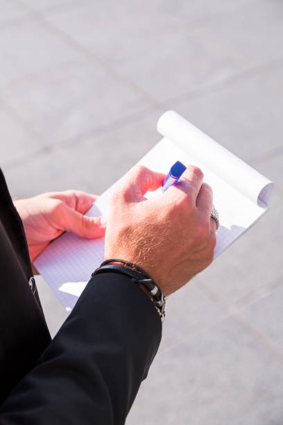 istock Male businessman or worker in black suit writing in notebook. 929037128