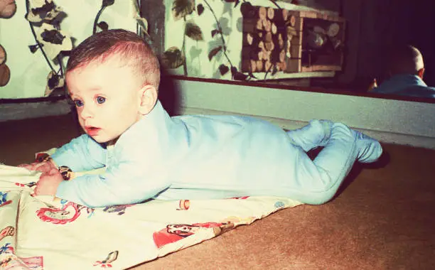 vintage color image of a cute baby boy laying on floor.