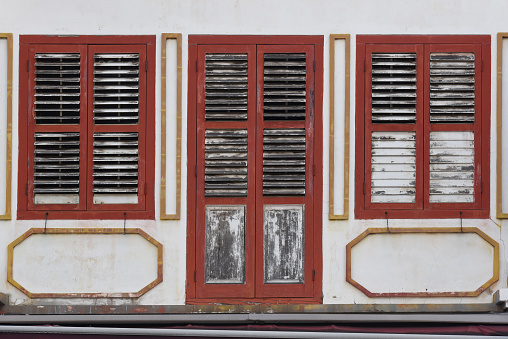 Red windows with shutters on white wall.