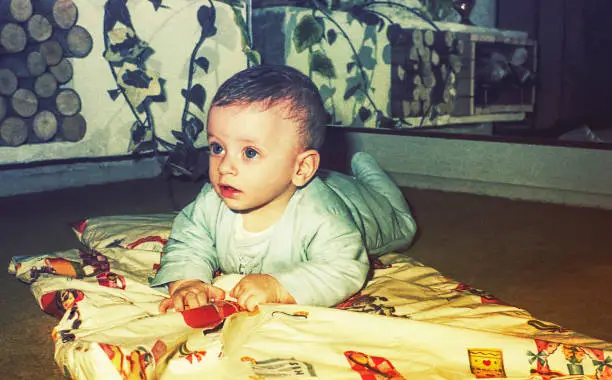 vintage color image of a cute baby boy laying on floor.