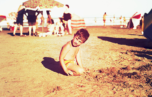 vintage and burnt color image of a little boy playing in the beach.