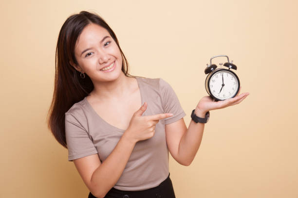 istock Young Asian woman point to a clock. 929061106