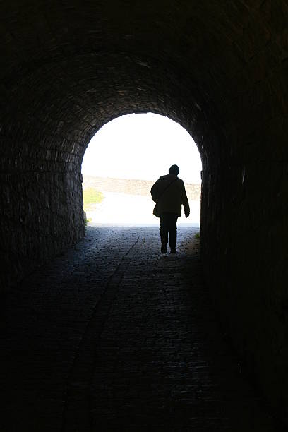 person in dark tunnel stock photo