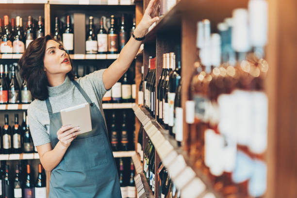 ワイン ショップで忙しい若い女性 - wine cellar liquor store wine rack ストックフォトと画像