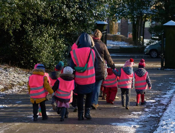 un grupo de pequeños escolares caminando al aire libre bajo la supervisión - road reflector fotografías e imágenes de stock