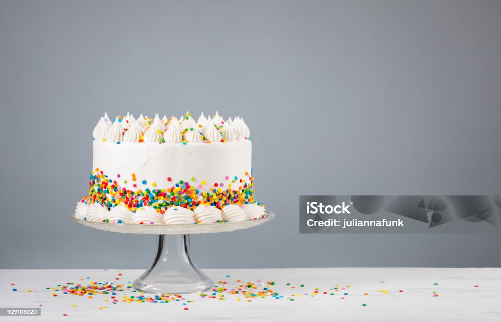 Birthday Cake with Sprinkles White Birthday cake with colorful Sprinkles over a neutral gray background. Cake Stock Photo