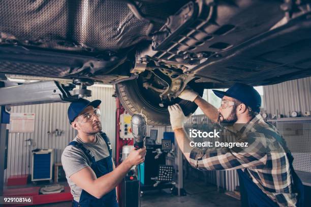 Engineering Protection Reliability Safety Oneness Colleagues Assistance Professionals In Blue Overalls Protective Spectacles Are Examining Changing Tires Tyres Brake Pads At Work Shop Stock Photo - Download Image Now