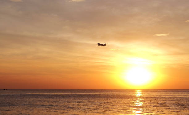 istock Silhouette of airplane flying over sea at the sunset 929110012