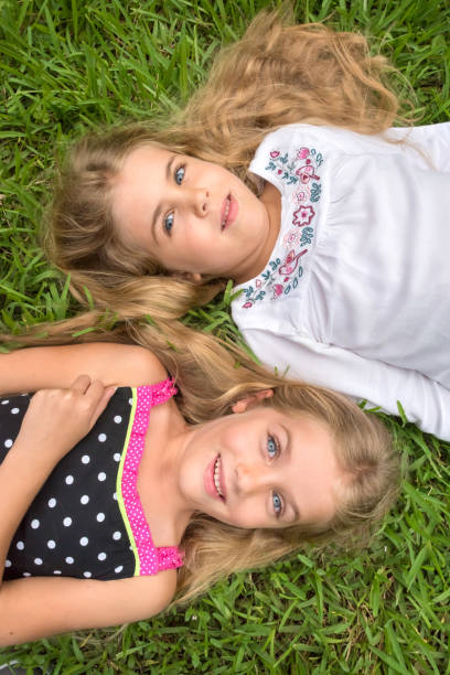 istock Little girls posing lying on the grass 929121450