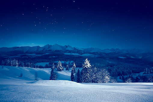 Starry winter night. Stunning night landscape. Sky full of stars over snowy mountains and valley.